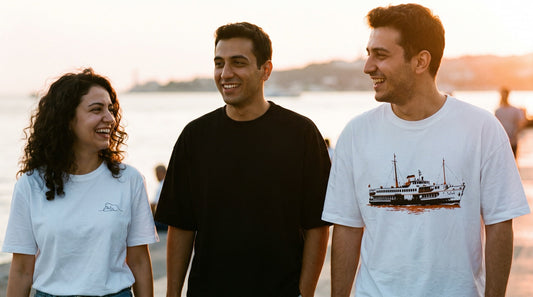 Moda sahilinde siyah ve beyaz tişörtlerle yürüyen üç arkadaş
