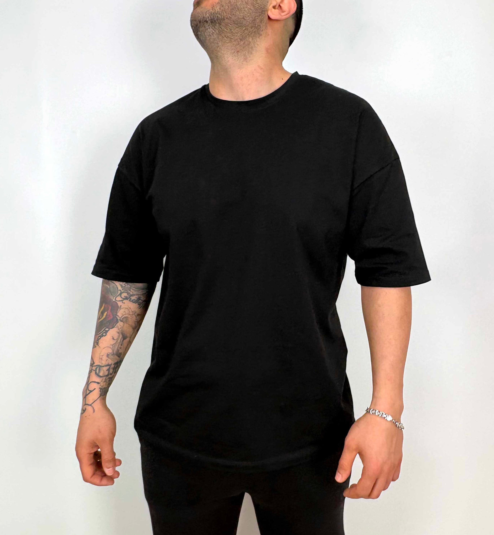 Siyah oversize tişört giyen erkek model önden